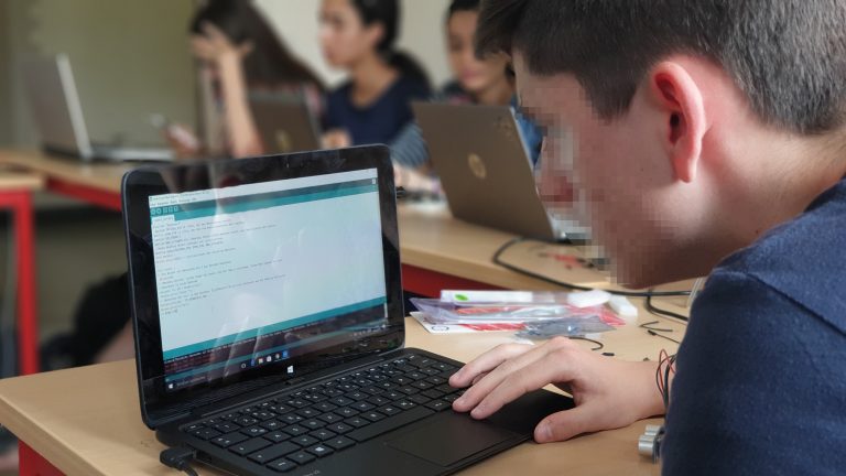 Schüler vor einem Laptop mit offenem Codeprogramm