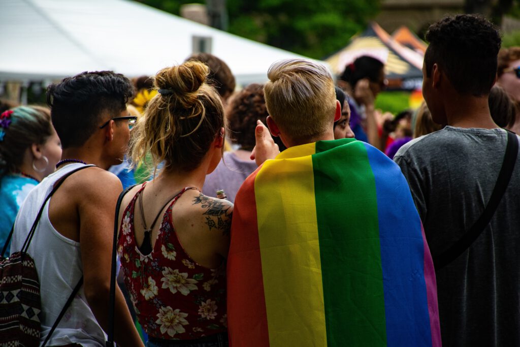 Menschen stehen eng beieinander und haben eine Regenbogenfalgge bei sich